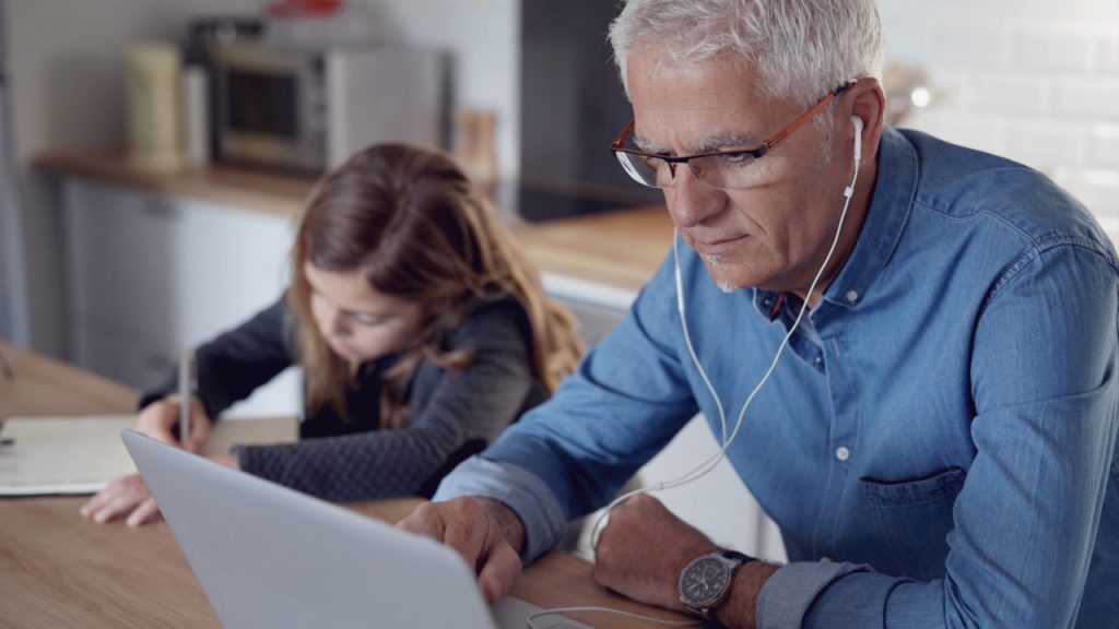 Father working on the computer while his daugter doing her homework
