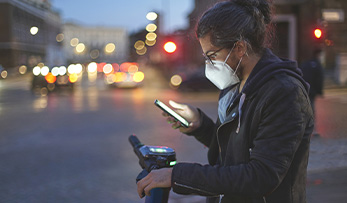 A man with a protective mask on his face looking at the phone.