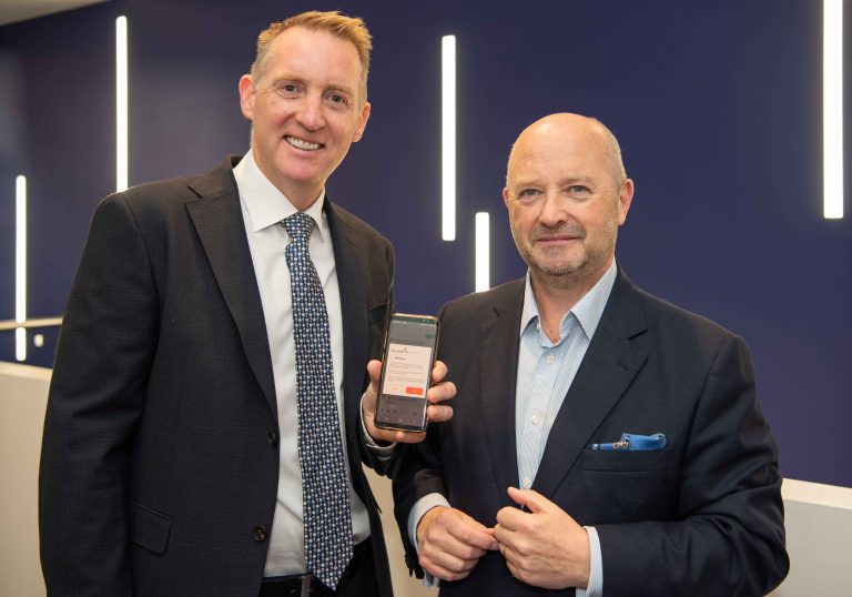 Two men holding a phone showing a phone