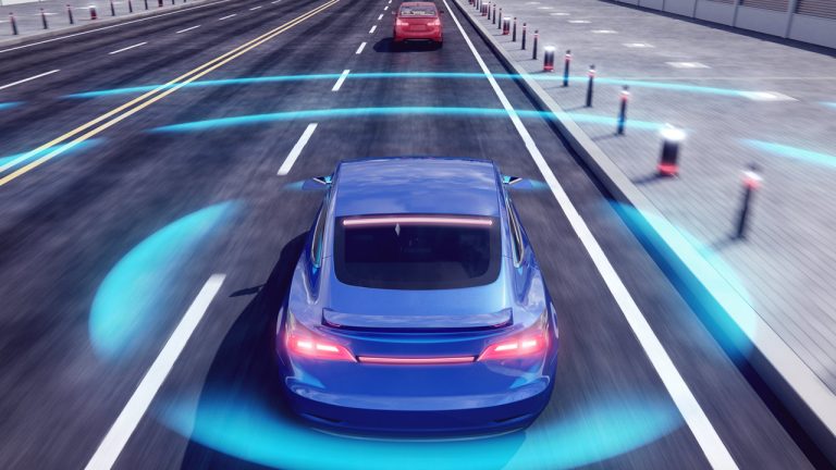 A blue car driving on a road with digital blue waves around it, illustrating autonomous or self-driving technology. Another car is visible ahead, and traffic cones line the right side of the street.