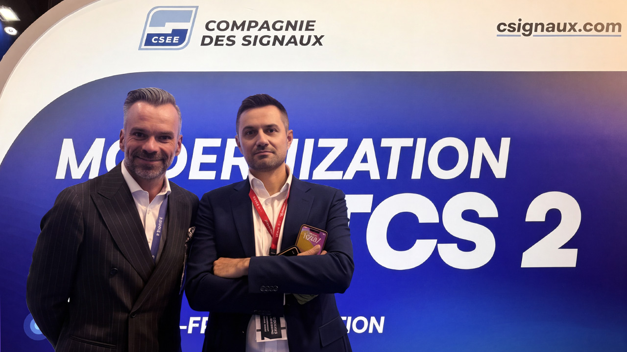 Zwei Männer in Anzügen stehen vor einem Messestand der „Compagnie des Signaux“.