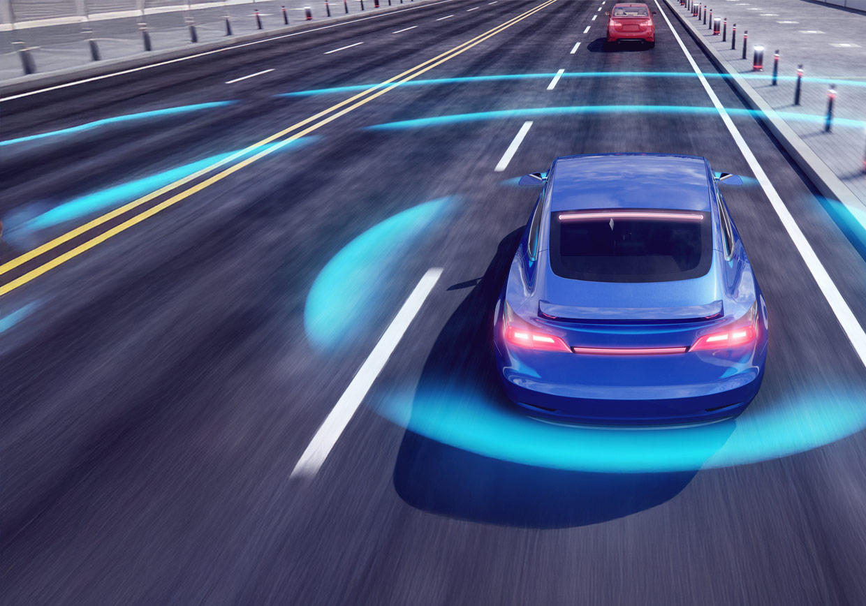 A blue car drives on a multi-lane road with blue sensor waves around it, representing autonomous or self-driving technology. Another red car is ahead in the adjacent lane, and traffic barriers line the road.