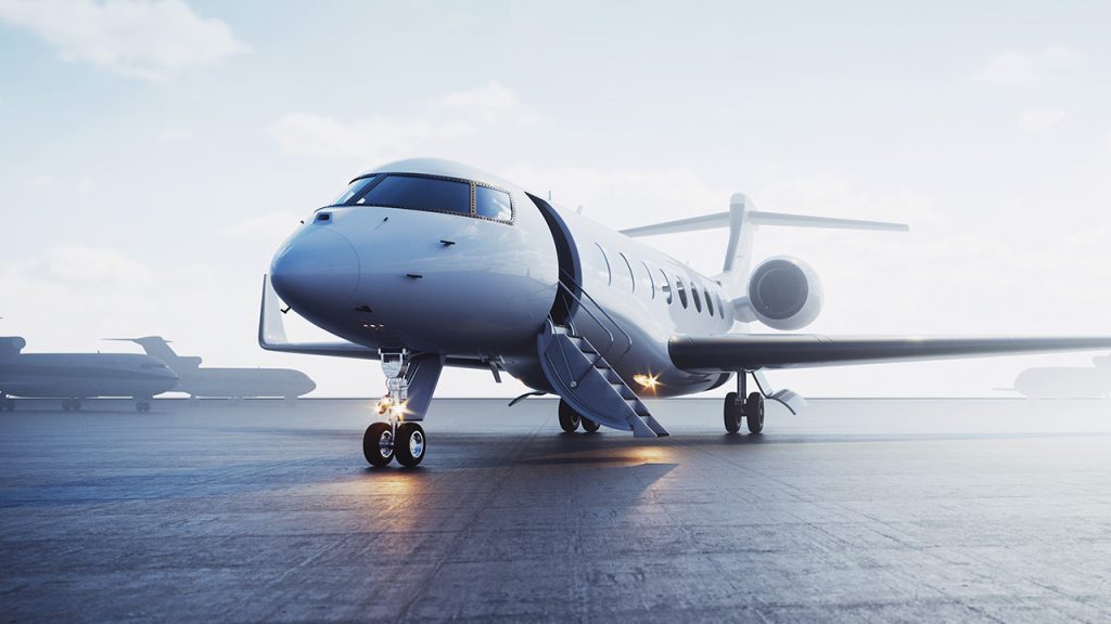 A sleek white private jet with stairs extended is parked on an airport runway, with other aircraft visible in the background under a bright, slightly cloudy sky.