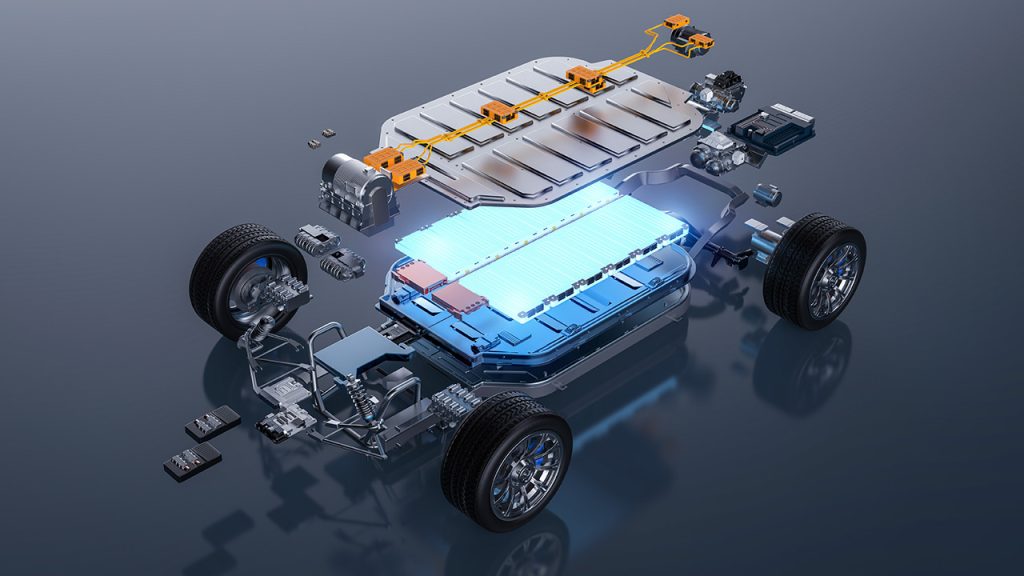 An exploded view of an electric vehicle chassis showing the battery pack, wiring, wheels, suspension, and various electronic components on a reflective surface.