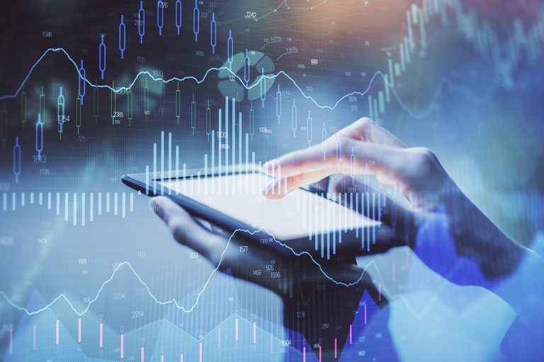 A person interacts with a tablet device, hands visible on the screen. Overlaid is a transparent graphic of financial data from IAA, featuring bar charts and line graphs illustrating stock market trends in blue and white hues. The background is blurred.