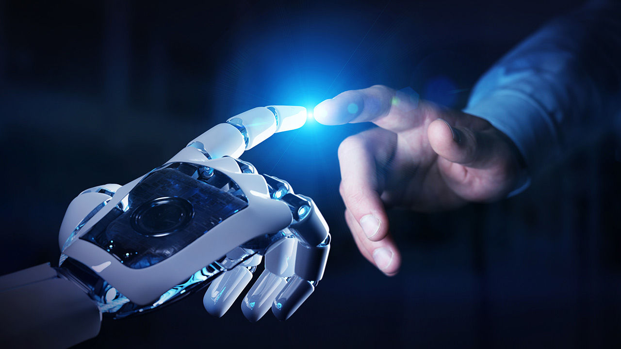 A robot hand and a human hand touching fingers in a dark background with a blue light in the center of the robot’s palm. The image suggests a futuristic and technological theme.
