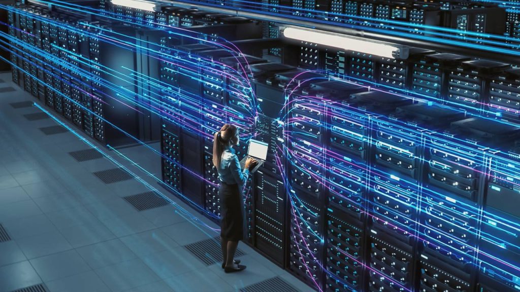 A professional woman using a tablet in a data center with rows of server racks, visually enhanced with glowing blue digital data streams swirling around her.