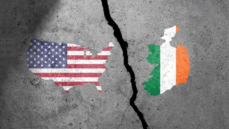 Two maps, one of the United States with its flag design and one of Ireland with its flag design, are separated by a jagged crack on a concrete surface.