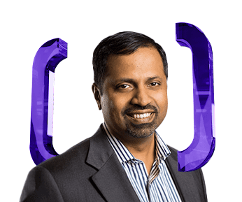 A man in a suit smiles at the camera, standing in front of two large, purple bracket symbols on a white background.