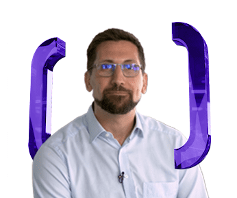 A man with glasses and a beard, wearing a light blue shirt, sits in front of a white background with large, translucent purple curly brackets on either side of him.