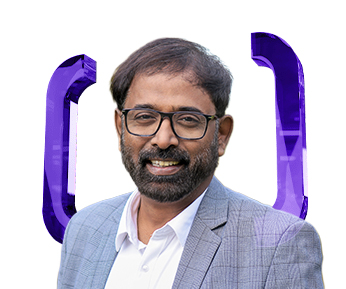 A man with glasses and a beard, wearing a gray checked suit jacket and white shirt, smiles in front of a white background with two large purple brackets behind him.