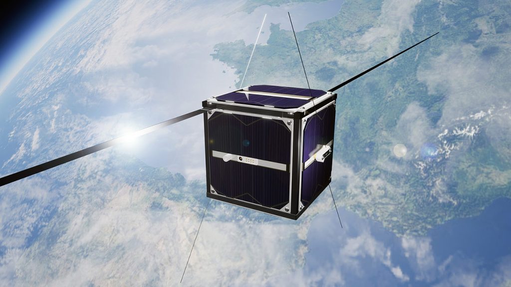 A small cube-shaped satellite with solar panels and antennas orbits above Earth, with the planet’s surface, clouds, and curvature visible in the background.