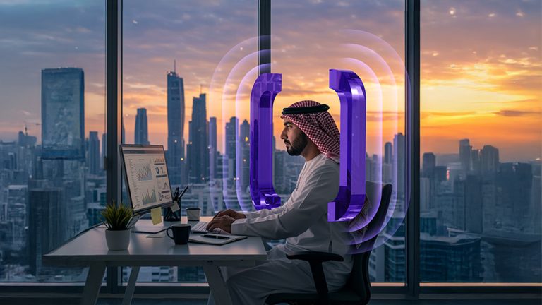 A man in traditional Middle Eastern attire works at a computer in a modern office with large windows overlooking a city skyline at sunset. Purple digital graphics surround him, symbolizing technology or connectivity.