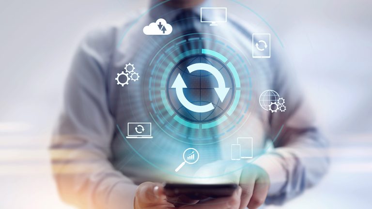 A person in a suit holding a mobile phone with digital icons, including arrows forming a circle, cloud, gears, and devices, representing concepts like synchronisation, technology, and data integration.