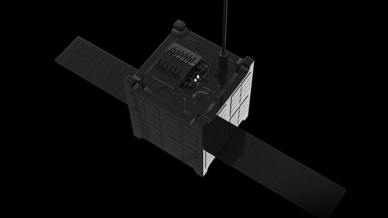 A small, black satellite with two extended solar panels and visible antenna, set against a black background. Developed by Expleo & Van Allen pour la recherche spatiale française, it has a boxy shape with detailed components on its top side.