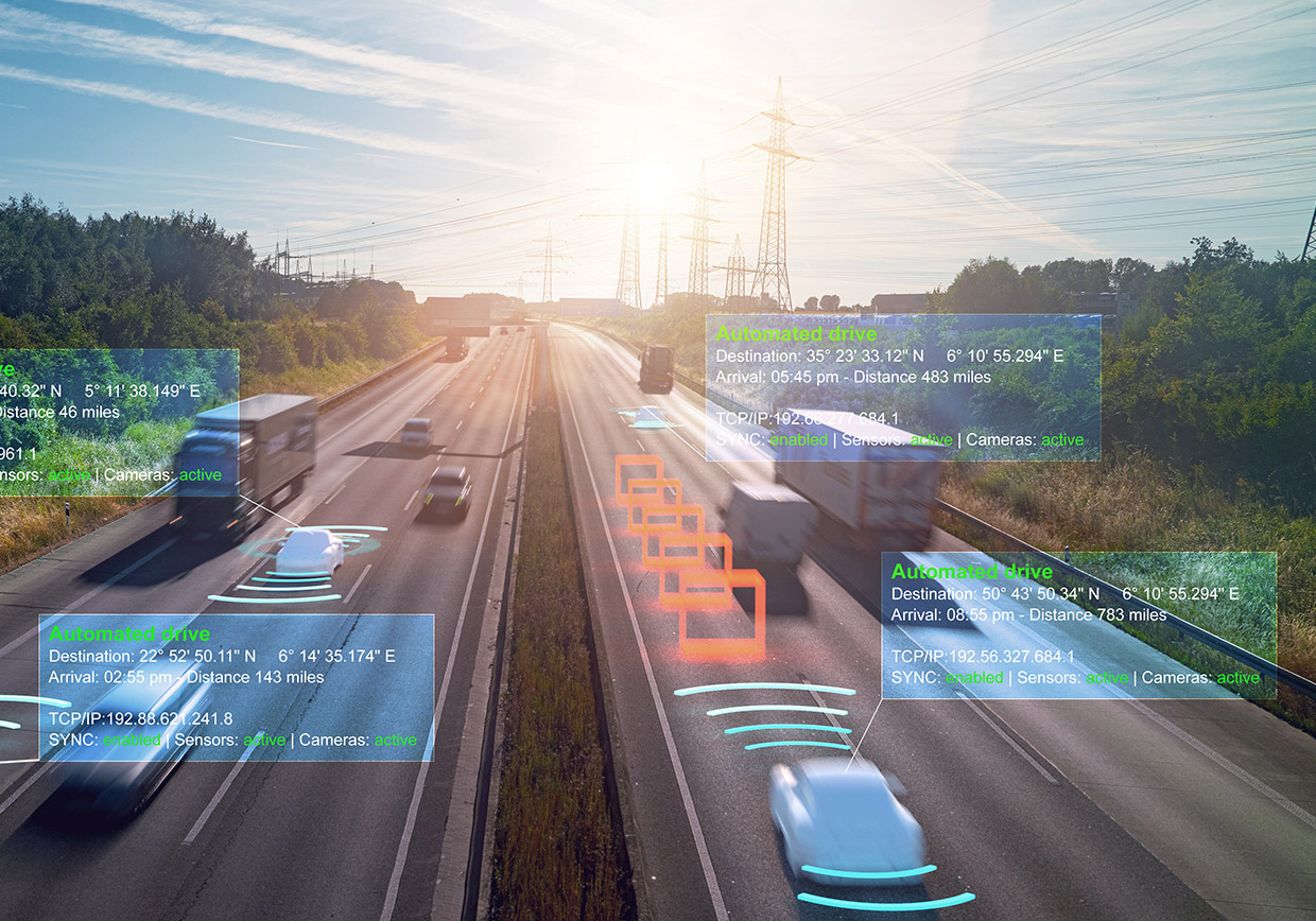 Cars and trucks drive on a highway at sunset, with digital overlays showing data such as location, speed, and sensor activity, illustrating autonomous vehicle technology and real-time vehicle-to-vehicle communication.