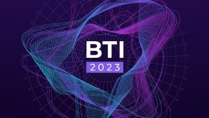 A vibrant, abstract digital design with flowing lines in shades of purple, blue, and pink against a dark background. The text in the center reads "BTI 2023." A faint circular grid is visible in the background.