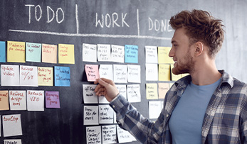 A young boy setting out his workflow for the day on a task board.