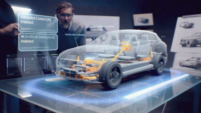 A man with glasses interacts with a futuristic holographic display showcasing a detailed car interior and mechanical system. Floating text highlights features such as Autopilot Control (AI) Enabled and AI (Artificial Intelligence) Enabled.